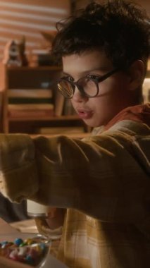 90 'lı yıllarda arkadaşıyla bilgisayar oyunu oynarken kola içen sevimli bir çocuğun dikey görüntüsü.