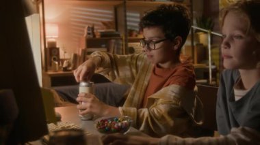 Kalın gözlükler takan ve arkadaşlarıyla video oyunu oynarken bilgisayar kullanan 90 'lı yaşlarda sevimli bir çocuğun görüntüsü.