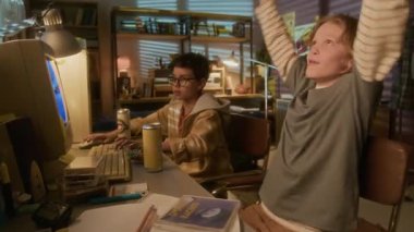 90 'ların çocukluk ortamında eski okul bilgisayarını kullanarak arkadaşlarıyla video oyunları oynarken sarışın bir gencin kutlama sahnesi.