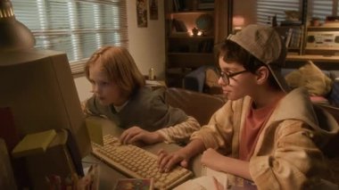 90 'ların çocukluk ortamında bilgisayar kullanırken video oyunu oynayan ve beşlik çakan iki çocuğun görüntüsünü büyüt