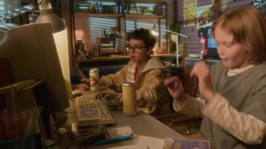 90 'larda eski okul bilgisayarını kullanarak arkadaşıyla video oyunu oynarken yenilgiye uğrayan sarışın çocuğun yan görüntüsü.