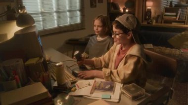 İki çocuğun video oyunu oynarken ve nostaljik 90 'lar setinde nostaljik bilgisayarla joystick kullanırken yan görüntüsü