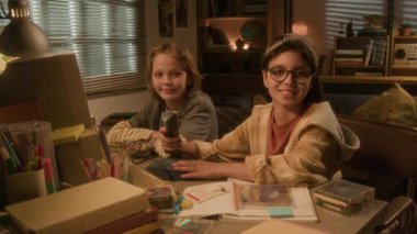 İki genç çocuğun nostaljik 90 'lı yıllarda bilgisayarla masada otururken kameraya gülümseyen portresi.