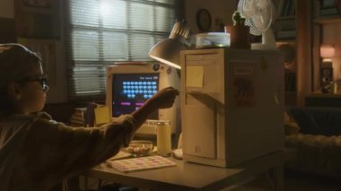 Genç bir çocuğun retro bilgisayara disket taktığı ve sıcak 90 'larda pikselli video oyunu oynadığı omuz üstü çekim.