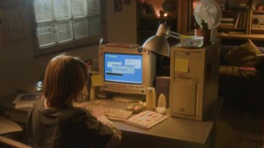 Sarışın çocuğun evde retro bilgisayar kullandığı yüksek açılı görüntüler. Klavyede 90 'lar ayarlı ve daktilo kullanıyor.