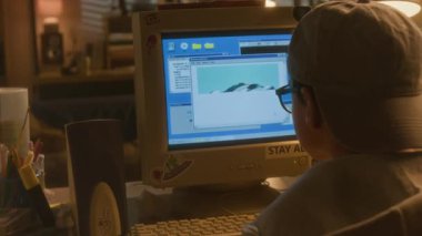 Çevrimiçi eski bilgisayarla arabaların resimlerine bakan genç bir çocuğun omuz üstü görüntüsü. Görüntüler yavaş yavaş internet üzerinden ekrana indiriliyor.