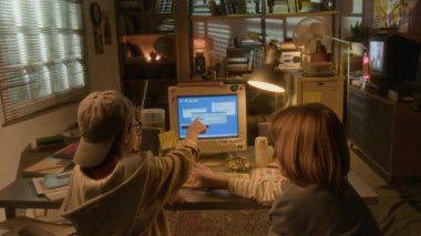 Ilık 90 'ların oda ayarlarında retro bilgisayar kullanan iki çocuğun geniş açılı arka görüntüsü