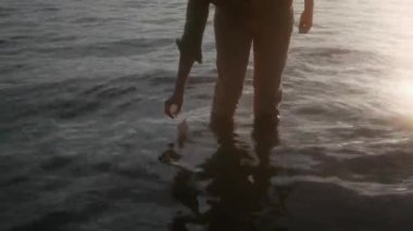 Haki gömlekli ve pantolonlu, parlak güneş ışığına karşı gölde duran kimliği belirsiz bir adamın orta kesiminde çekilmiş bir fotoğraf.