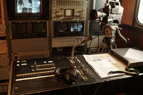 Mikrofon, kulaklık, senaryo metni ve ses karıştırma konsolu ile düğmeler ve düğmeler üzerindeki yayın programı