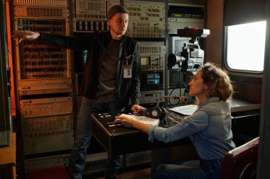 Genç adam ekranda yeni bir sicile işaret ediyor ve tartışma sırasında bayan iş arkadaşının detaylarını anlatıyor.