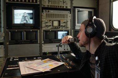 Genç erkek operatör mikrofonla konuşuyor ve meslektaşı ile birlikte haber kanalı için röportaj yapıyor.