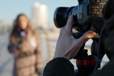 Kadın gazetecinin önünde dikilirken kameraya odaklanan tanınmayan genç erkek operatörün eli