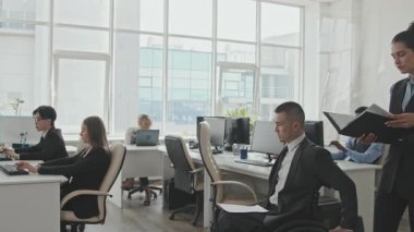 Tekerlekli sandalyedeki çok ırklı erkek iş adamının yavaşlığını takip ediyor. Masalarda oturan yöneticileri selamlıyor ve kadın kişisel asistanı tarafından kendisine verilen belgelere bakıyor.