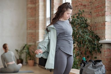 Spor salonunda yoga eğitimine hazırlanırken kızın ceketini çıkarmasını engelle