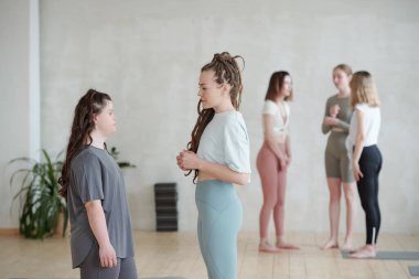 Yoga antrenmanından sonra üç kızın konuşmasına karşı eğitmenine danışan engelli genç bir kadın.