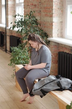 Spor salonunda, spor salonunda akıllı telefon kullanarak aktif giyimde bayanı devre dışı bırak