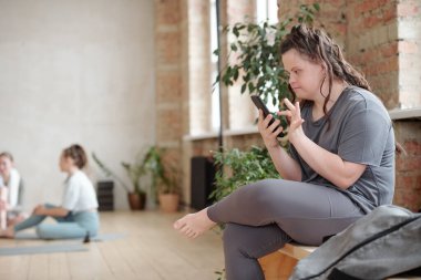 Spor salonundaki eğitimden sonra cep telefonunda kayan genç engelli kadın