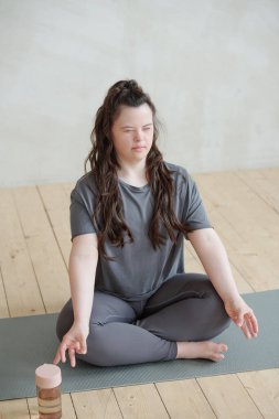 Beden dersinde paspasın üzerinde otururken meditasyon yapan gözleri kapalı genç bir kadın.