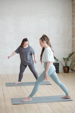 Genç antrenör, egzersiz sırasında yoga egzersizlerinden birini engelli kadın olarak gösteriyor.