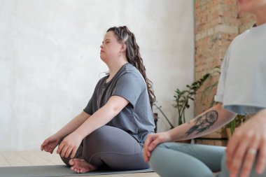 Beden dersinde yoga egzersizi sırasında dengesini koruyan gözleri kapalı bir kız.