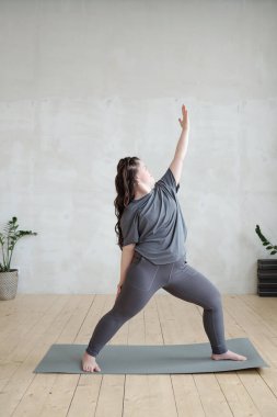 Antrenman sırasında spor salonunun zemininde kolunu gergin tutan genç bir kadın.