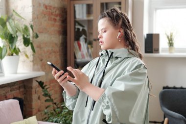 Kulağında kulaklık olan bir kızın akıllı telefondaki çalma listesini karıştırmasını engelle