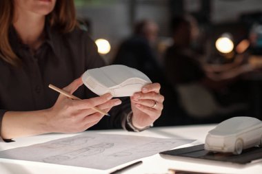 Yenilikçi büronun genç bayan tasarımcısının elleri. İş yerinde oturmuş, çizimler yapıyor ve yeni araba modelinin özelliklerini inceliyor.