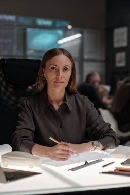 İş yerindeki yeni otomobil modellerini çizerken kameraya bakan genç ciddi iş kadını