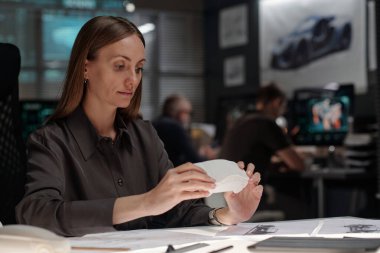 Yenilikçi büro projesinde çalışırken yeni modellere bakan kendine güvenen genç kadın tasarımcı.