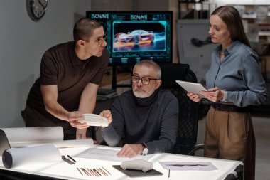 Genç erkek mühendis tabletle bayan meslektaşına bakarken buluşmadaki yeni araba modelini tanımlıyor.