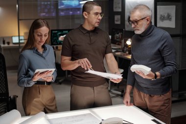 Araba mankenli olgun erkek mühendis sunum sırasında genç astın çizimi kağıt üzerinde göstermesini dinliyor.