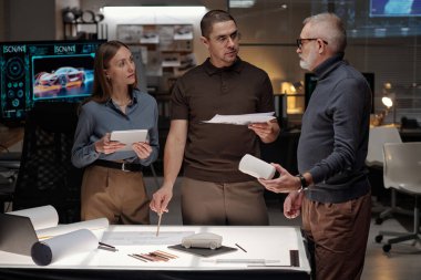 Büro 'da çalışan ve yeni projeyi veya sunumu tartışan kendinden emin üç tasarımcıdan oluşan bir grup