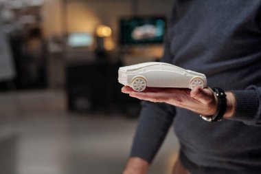 Yeni projenin sunumu sırasında araba modelini elinde tutan tanınmayan erkek otomobil tasarımcısının görüntüsü.