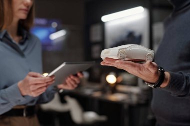 Erkek mühendis veya tasarımcının sunum sırasında elinde tabletle iş kadınının önünde duran araba modeli