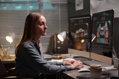 Bilgisayarın önünde işyerinde oturan ve 3D grafik çizimi olan ekrana bakan zarif genç otomobil tasarımcısı