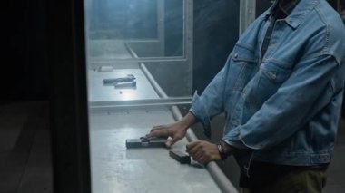 İçerideki hedeflere ateş eden farklı vatandaşlardan oluşan bir yan ortam. Kot ceketli ve kamyoncu şapkalı Afro-Amerikan bir adam şarjöre mermi dolduruyor, nişan alıyor, beyaz bir erkek onu oyalamaya geliyor.