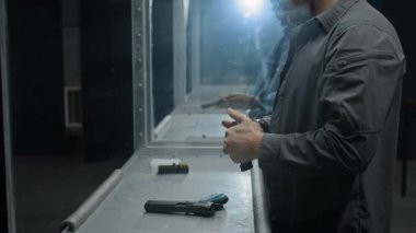 İki Afro-Amerikan ve Kafkas erkek arkadaşının kulaklık takıp kapalı alanda atış talimi yapması, silah doldurması, hedeflere nişan alması ve sohbet ederken ateş etmesi.