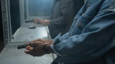 Çeşitli Afrika kökenli Amerikalı ve Kafkas kökenli genç erkeklerin el ve yüzlerinin yakın çekimleri, atış poligonlarında pratik yapmak, tabancalarla cephane yüklemek, nişan almak ve ateş etmek.