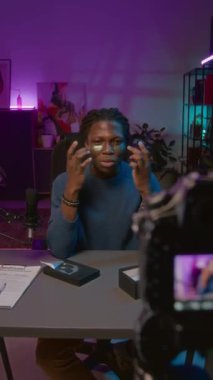 Sosyal medyada canlı yayın sırasında nemlendirici göz bantları test eden genç Afrikalı Amerikalı erkek yaşam tarzı blogcusunun orta boy dikey görüntüsü, kozmetik markasını tanıtırken,