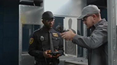 Beyaz erkek eğitmen, eğitime başlamadan önce Afrika kökenli Amerikalı polis memuruna doğru kulaklık taktığını gösteriyor.