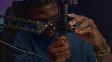 Genç Afro-Amerikan erkek flamanın yüzü ve elleri kayıt stüdyosunda, kabloyu mikrofon prizine takıyor ve canlı yayına hazırlanırken,