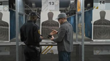 Kafkas erkek eğitmenin antrenmandan önce Afrikalı Amerikan polis akademisine konuşan orta boy arka zoom kulaklık taktığını ve kulaklık taktığını gösteriyor.