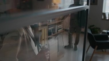 Cam bölme duvarının arkasında bekleyen, cam camda yansıması olan okul psikologunun ofisine girmekten korkan, baş belası küçük çocuğun yan görüntüsü.