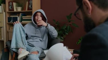 Erkek psikoterapistin, okul baskısından ya da aile sorunlarından bahseden kapüşonlu ergen beyaz kızı dinlerken omuz üstünden çekilen fotoğrafı.