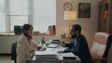 Erkek sakallı psikoloğun modern ofiste şık kızıl saçlı bir kızla çalışırken çekilmiş bir fotoğrafı. İkisi de masada oturup gelecekle ilgili konuları tartışıyor.