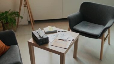 Elinde mendil, kâğıt ve kitap olan iki gri sandalyeli rahat terapi ofisinden çekilen insanlar yok. Derin sohbetler için ideal bir ortam.