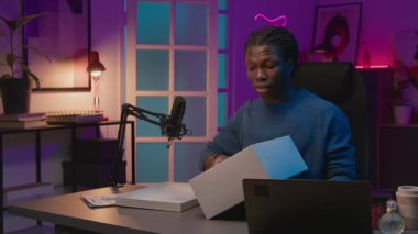 Sosyal medyada ya da online dükkanda canlı yayın sırasında spor eğitmenleriyle birlikte kutuları açan gülümseyen Afrikalı Amerikalı erkek blog yazarı, tasarım özelliklerine işaret ederek ve faydaları tanımlayarak