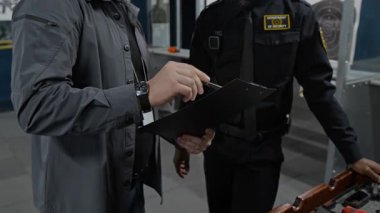 Şen şakrak erkek şut koçu ve mutlu zenci polis memuru, nişancılık kursunu bitirdikten sonra sınav sonuçlarını tartışıyor, tebrik ediyor ve tokalaşıyor.