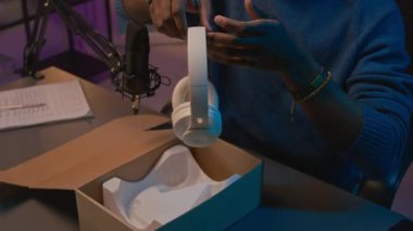 Afrika kökenli Amerikalı mutlu erkek nüfuzlu kişinin yakın plan çekimleri beyaz kulaklıkların yeni modelini çözerken canlı yayında kutuları açıyor, deniyor ve gülümsüyor.