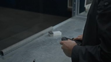 Beyzbol şapkası ve kulaklığı olan beyaz adamın yüz ve ellerinin yana yatık duruşu yarı otomatik silaha mermiler yerleştiriyor, ateş ediyor, atış talimi yaparken hedef alıyor ve atış talimi yapıyor.